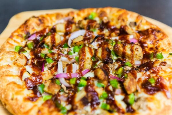 Delicious barbecue bbq drizzle chicken pizza with onions and green peppers closeup